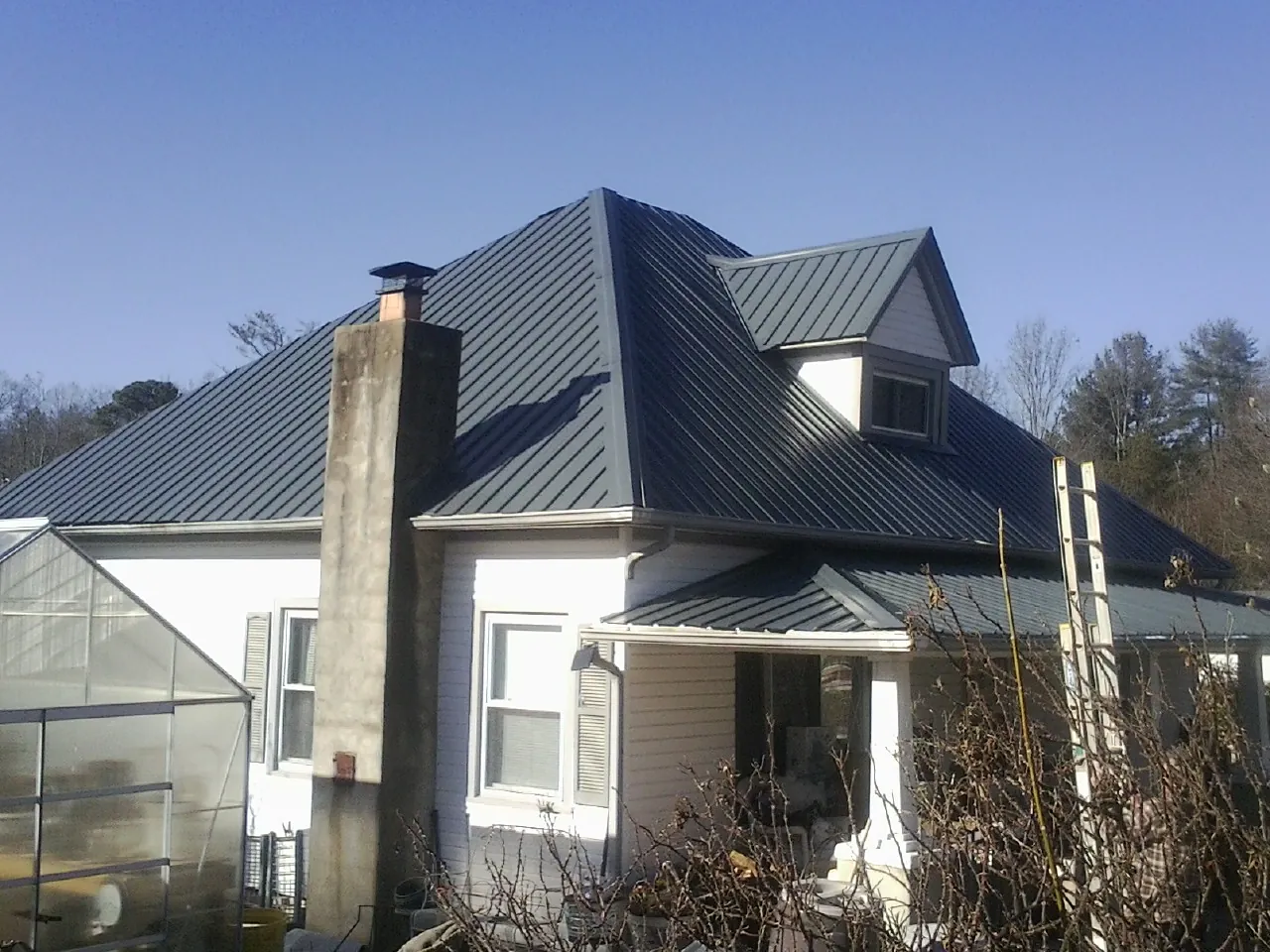 Dark blue standing seam metal roof on a white farmhouse with dormer — Slate & Tile Roof Repair by Roofing Brothers in Earleton
