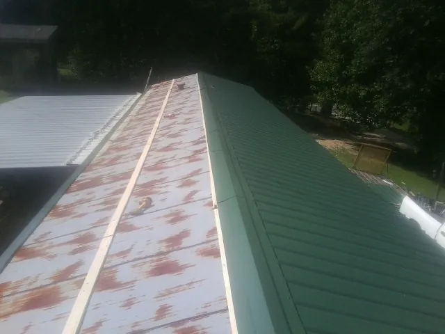 Old rusted panels beside newly installed green metal roofing — Wind Damage Roof Repair by Roofing Brothers in Earleton