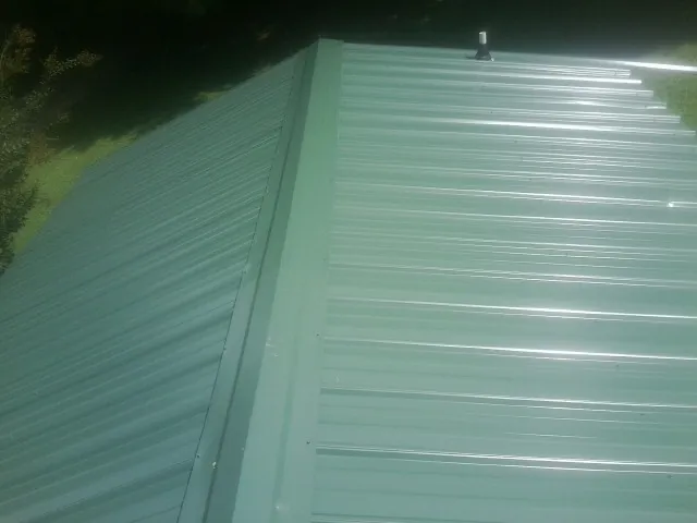 New green metal panels meeting at the ridge of a roof — Flat Roof Repair work by our crew in Earleton